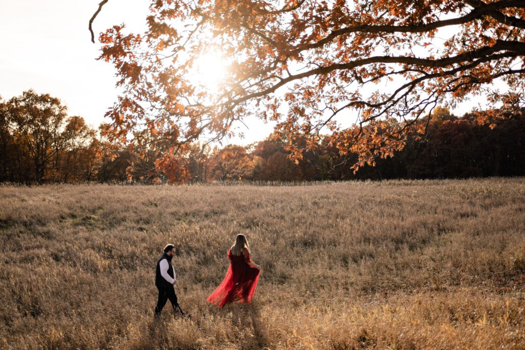 an expecting couple wander through an open field as one of the maternity photographers in michigan captures them