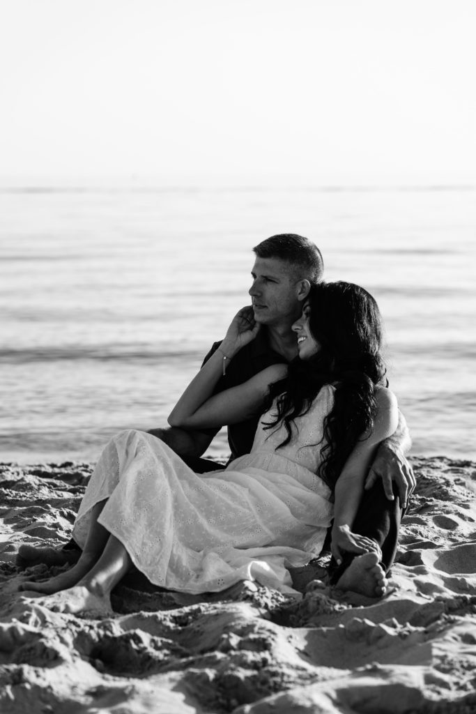 grand haven photographers capture this engaged couple lounging in the sand at the beach