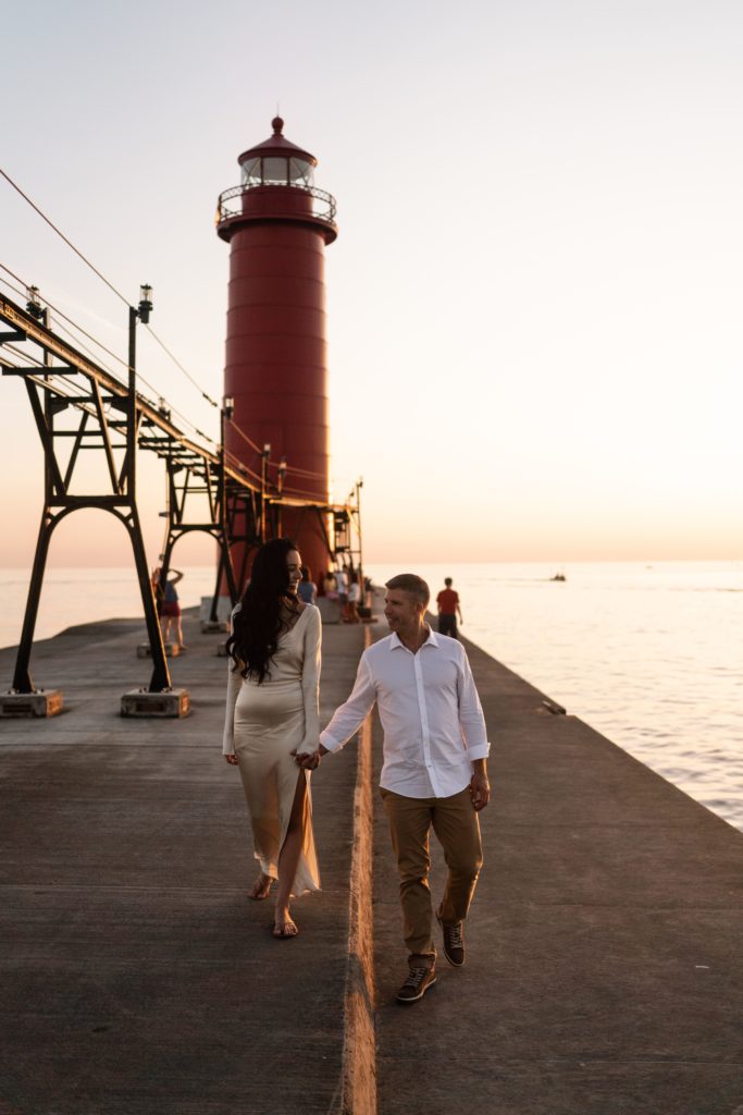 an engaged couple walk along the grand haven pier for their michigan engagement photos