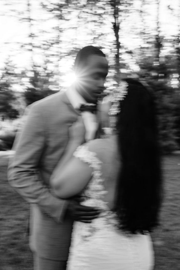 the luxury wedding photographer captures a motion blur black and white portrait of the newlyweds leaning into each other