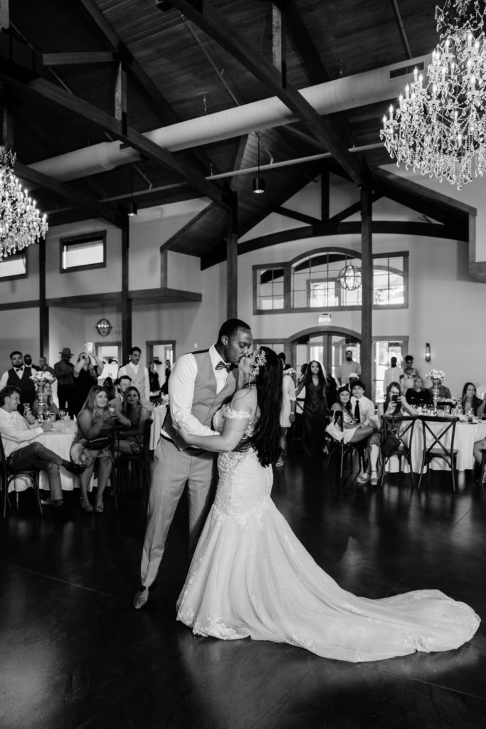 the bride and groom share a kiss during their first dance at black river barn in south haven michigan, their wedding venue