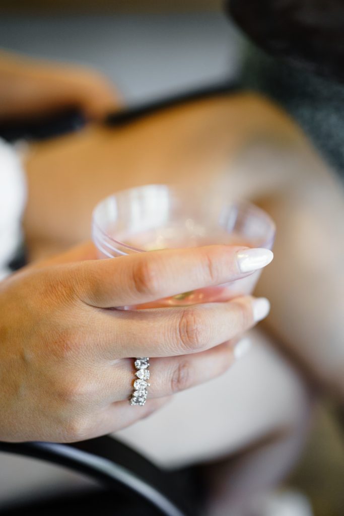 luxury wedding photographer captures a close up of the bride holding a drink with her engagement ring and wedding nails on display