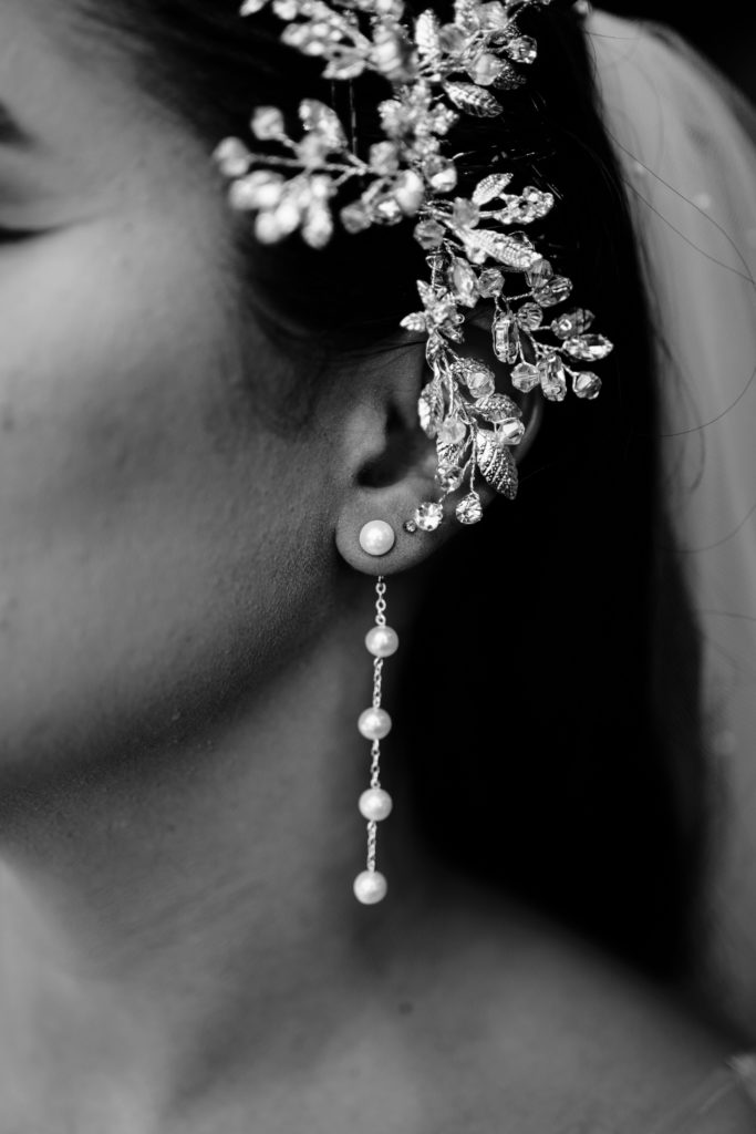 a black and white portrait of the bride's hair accessory and pearl drop earrings taken by luxury wedding photographer