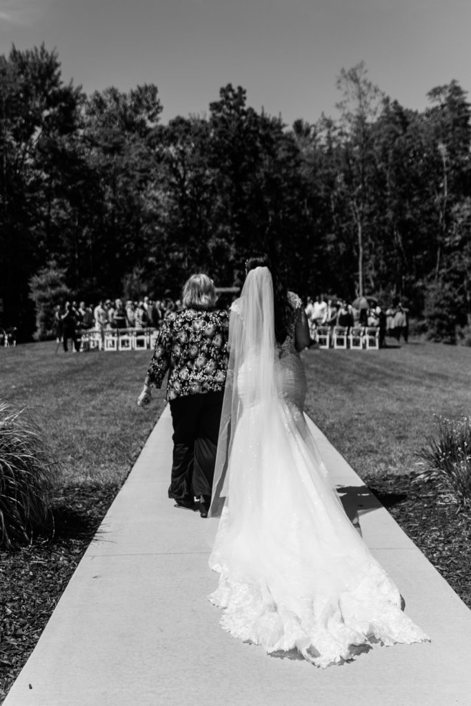 luxury wedding photographer documents the moment as the guests turn to look at the bride, escorted by her mother walk down the aisle