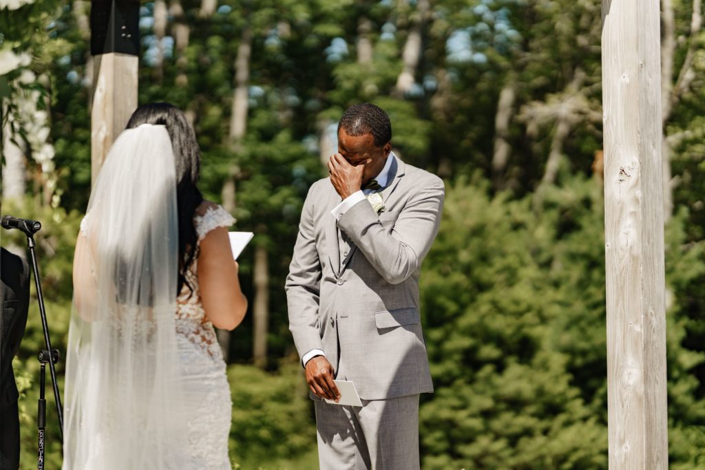 the groom covers his eyes as he gets emotion during his wife's vows while their luxury wedding photographer captures the feeling