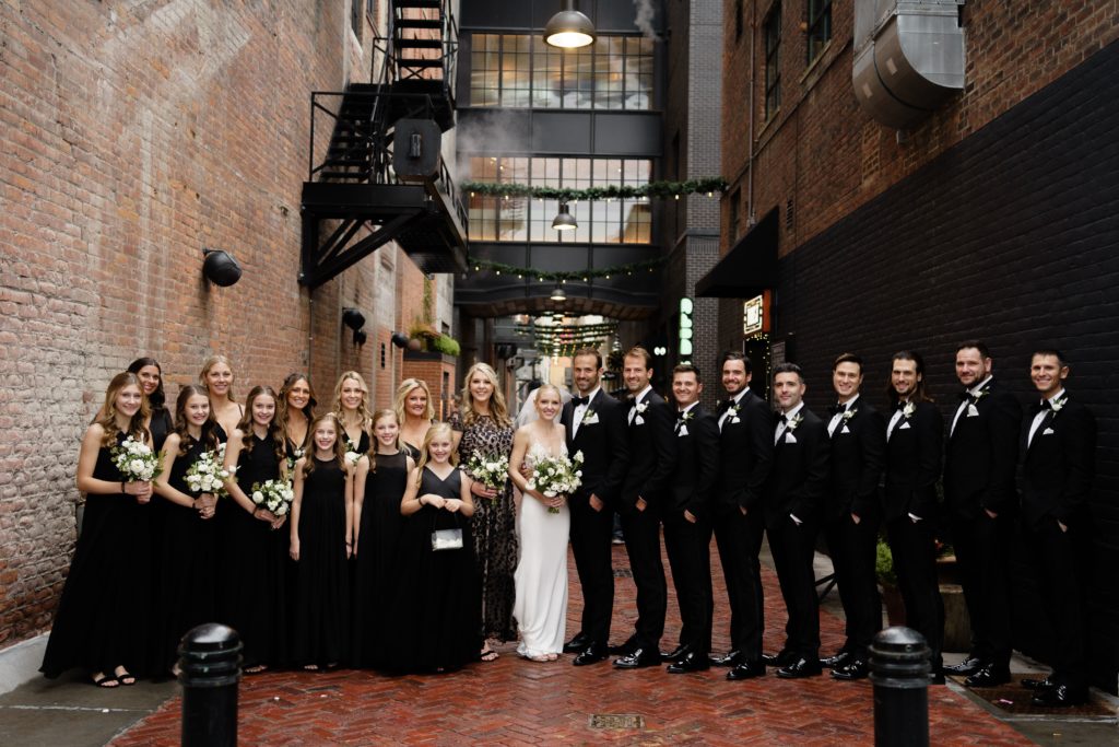 the wedding party stand neatly lined up in a brick lined alley posing for a detroit wedding photographer