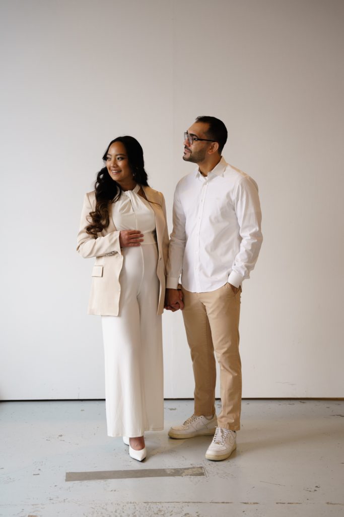 an expectant couple stand holding hands at their luxury maternity photoshoot