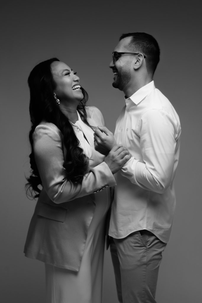 expectant couple laugh together during their indoor maternity shoot