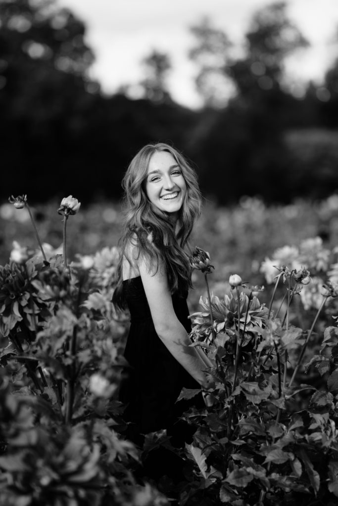 louise laughs in a field of flowers during for her editorial senior pictures