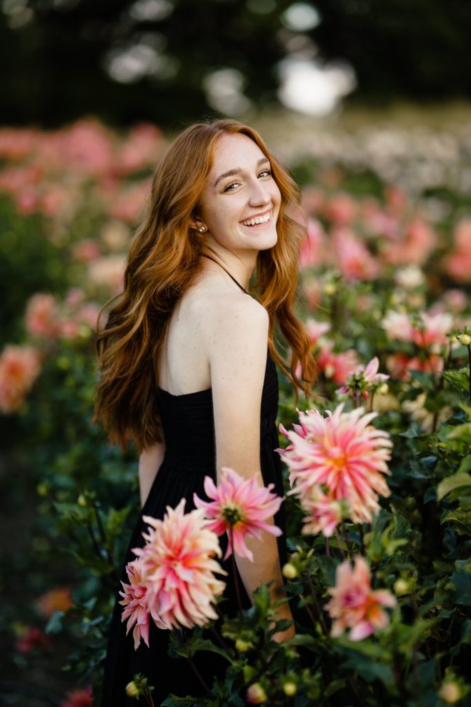 louise laughs while standing in a field of flowers for her senior portrait photography