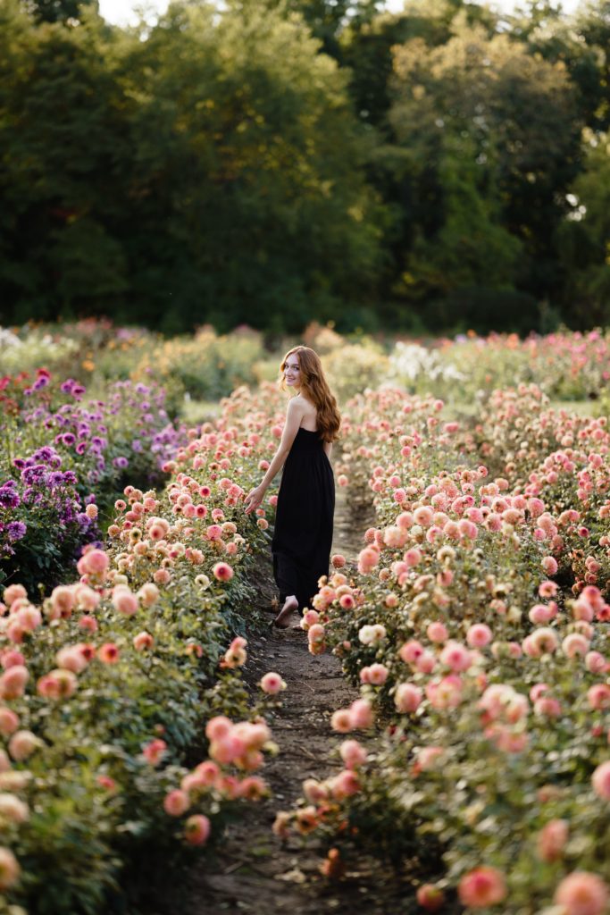 louise looks back as she walks through a flower field during her editorial senior pictures
