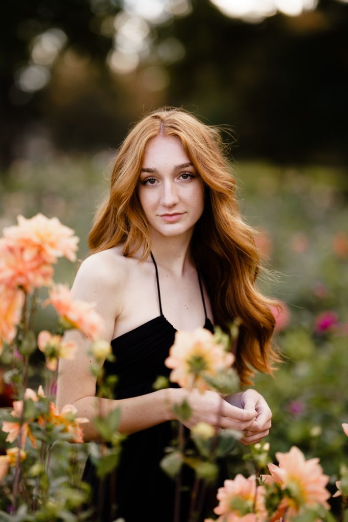 louise smiles softly in a flower field while posing for her senior portrait photography