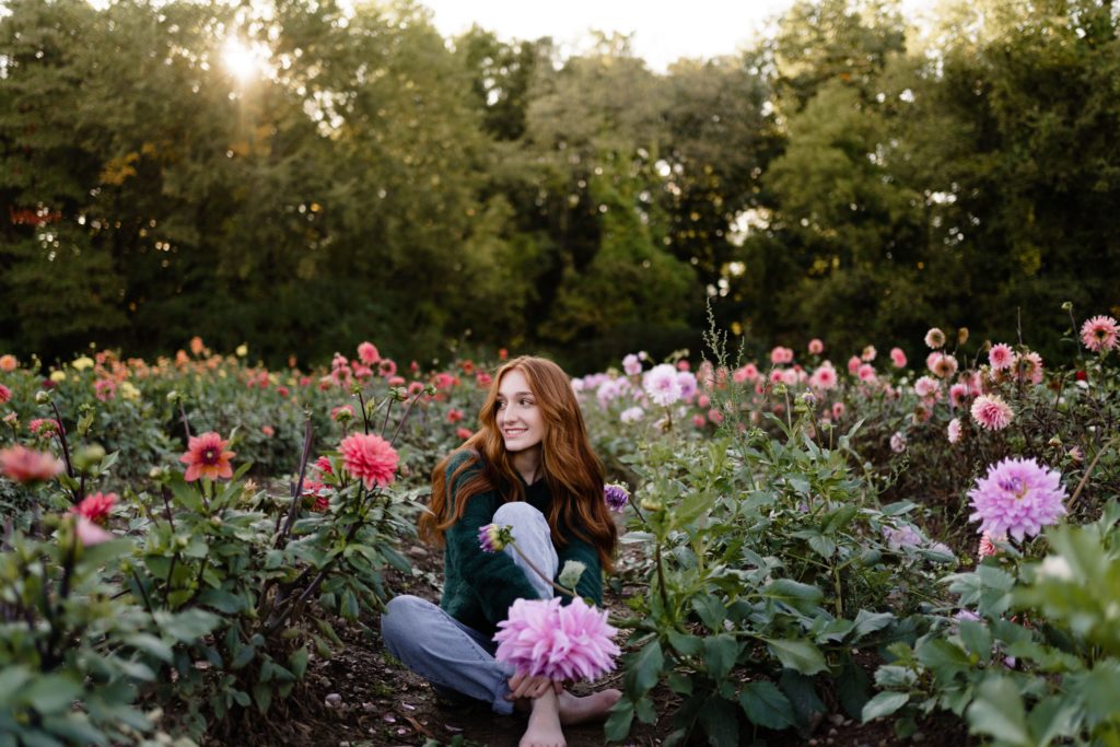 louise sits in a flower field senior pictures