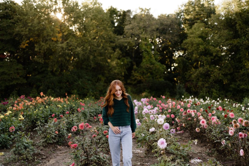 louise looks down as she stands in a flower field senior pictures