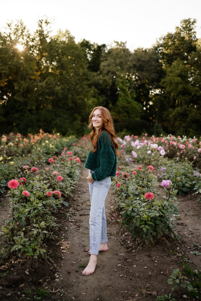 louise smiles while standing in a field of flowers for her senior pictures detroit