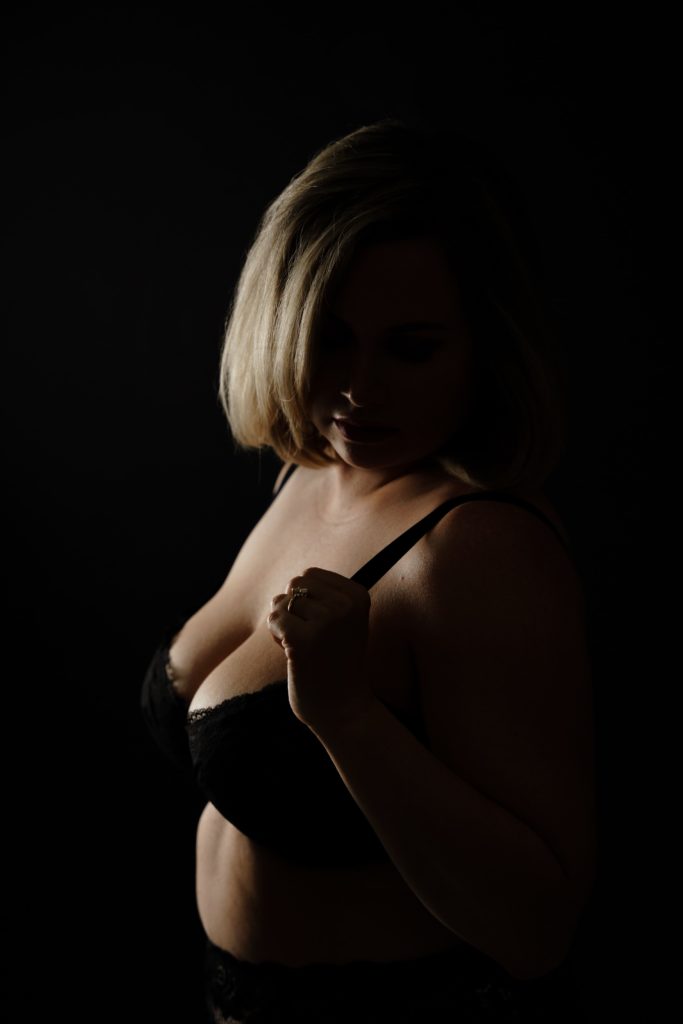 jo stands in a spotlight during her boudoir photoshoot