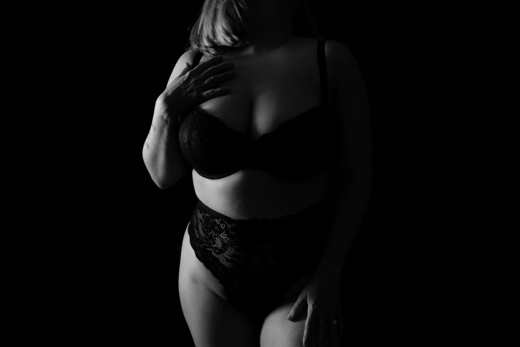 jo stands in front of a boudoir photographer wearing a black lingerie set