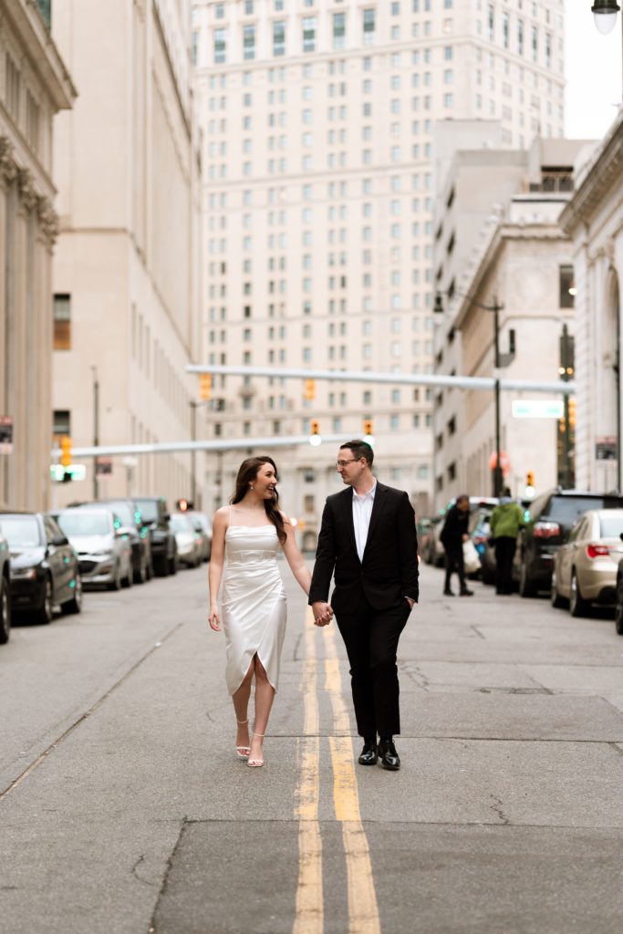 julia and drew hold hands in the middle of a downtown detroit street