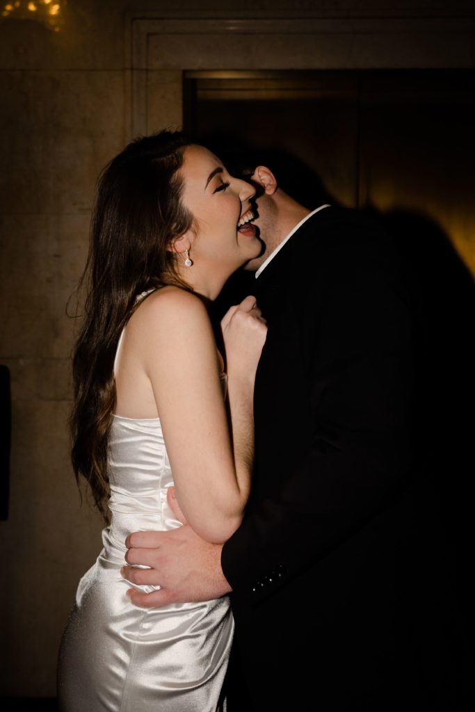 drew presses a kiss to a laughing julia's neck by the elevator at the detroit foundation hotel