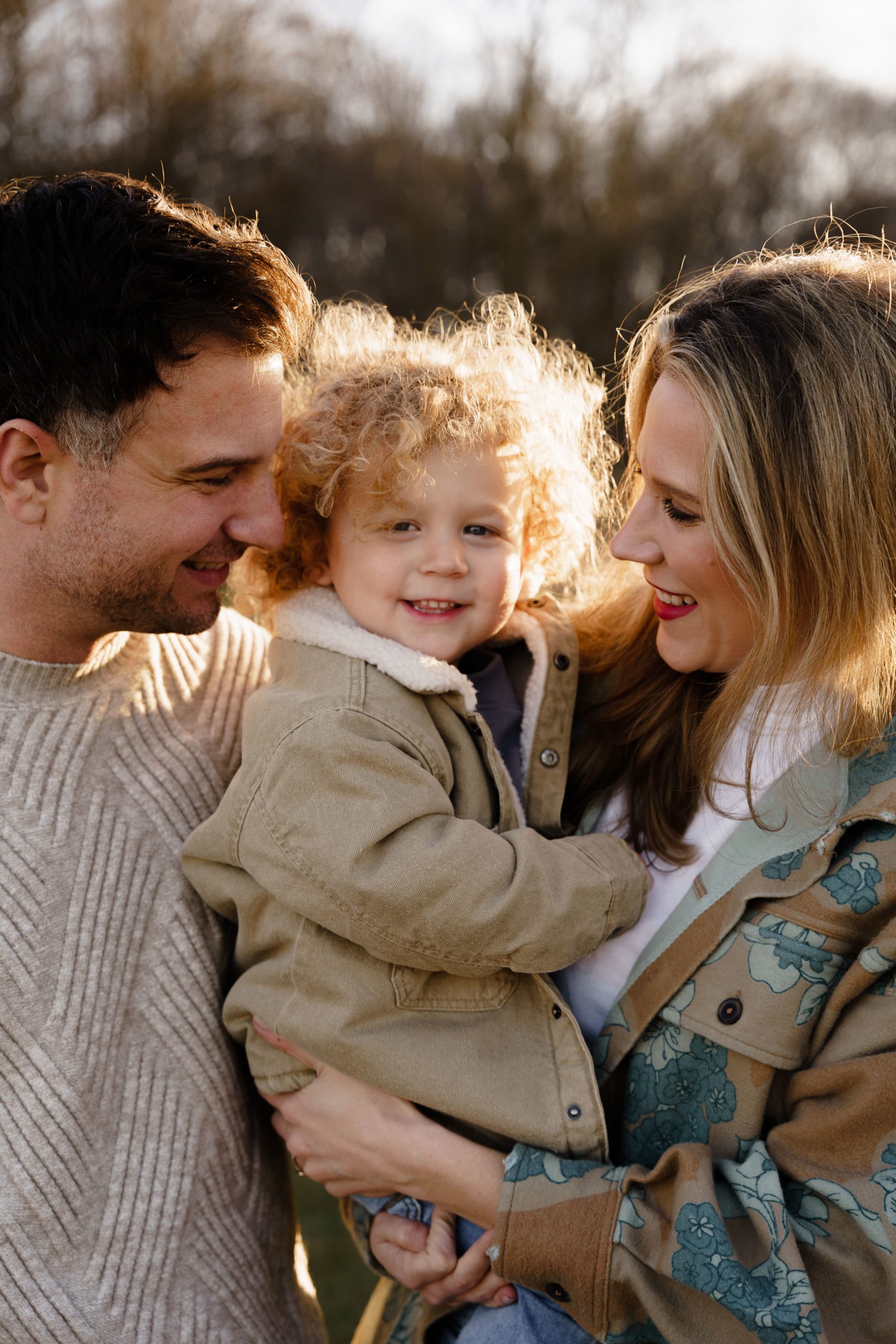 a family of 3 smile together during their session with a family photographer