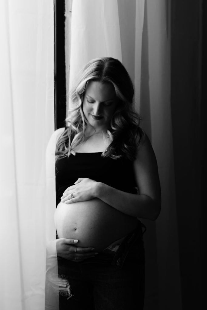 a sweet portrait of a mother smiling at her belly during a maternity photoshoot