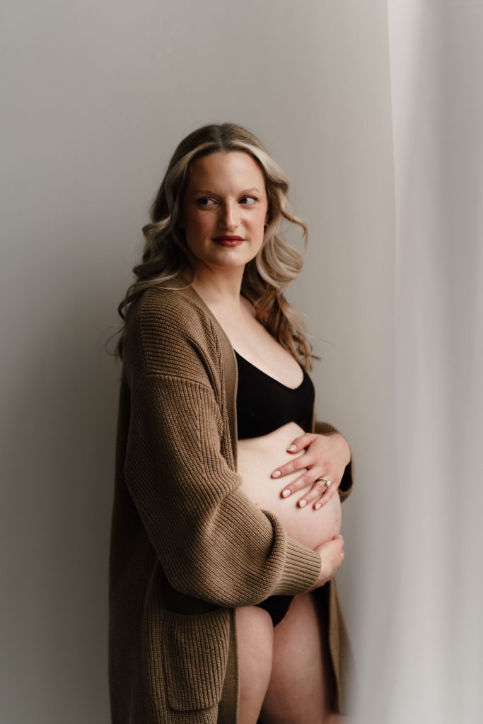 michigan maternity photographer captures an expecting mother in a cozy cardigan + cozy lingerie set