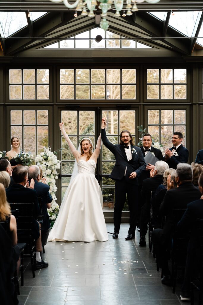 the bride and groom cheer at the end of their wedding ceremony at royal park hotel in michigan