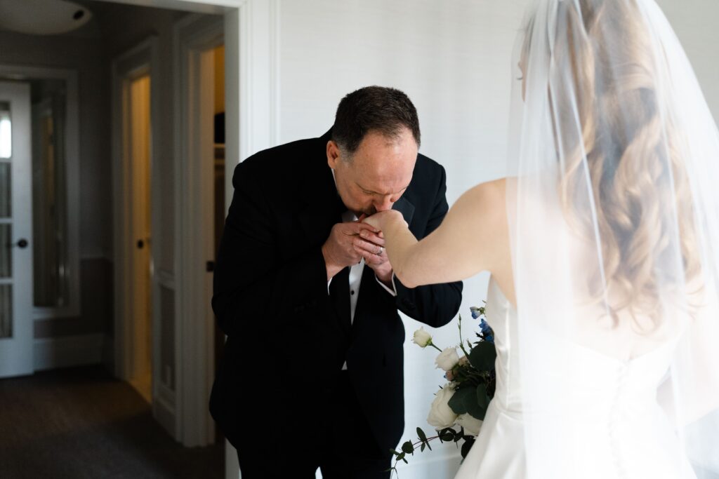 the bride's father kisses her hand during their emotional first look