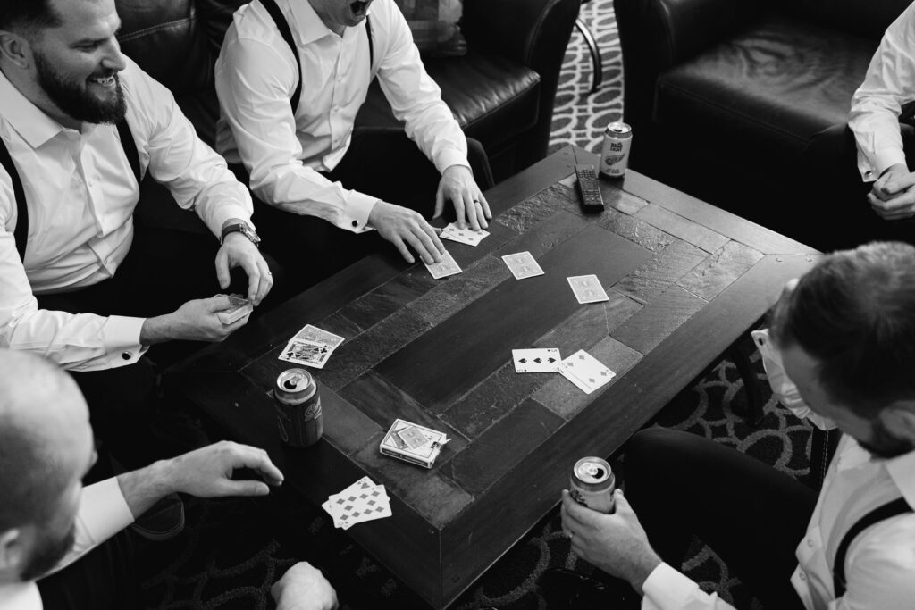 the groomsmen play cards while getting ready for the ceremony