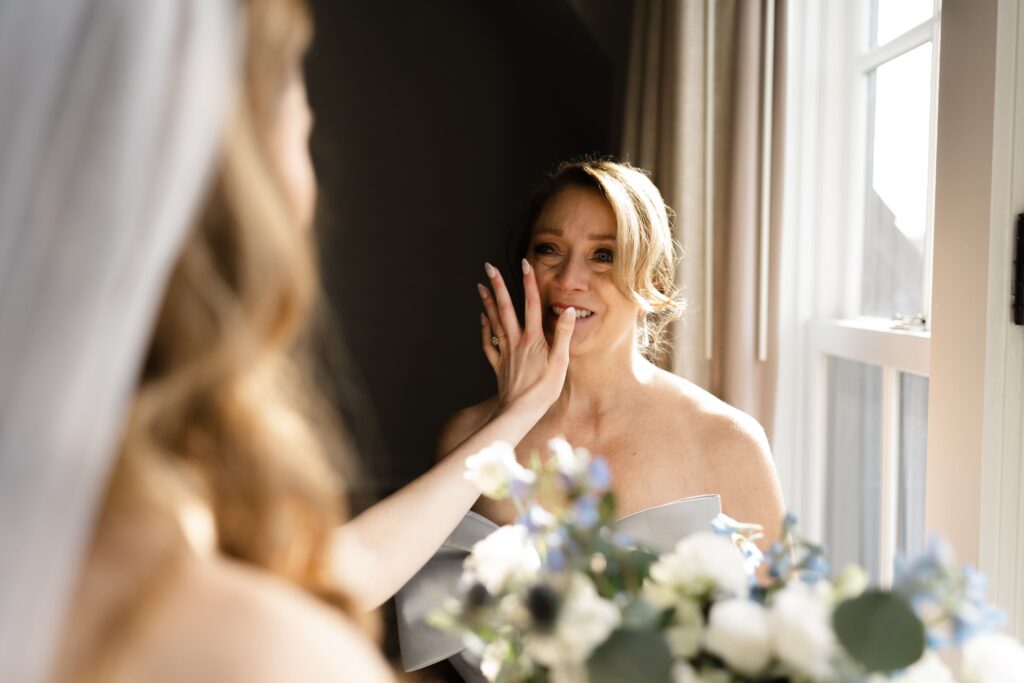 the bride wipes tears from her mother's eyes before her wedding ceremony