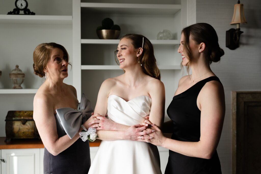 the bride smiles with her mother and maid of honor