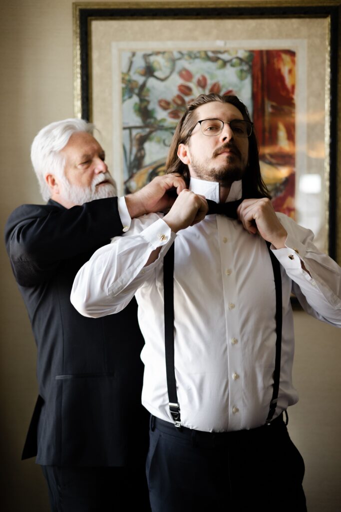 the groom's father helps him get ready for his wedding