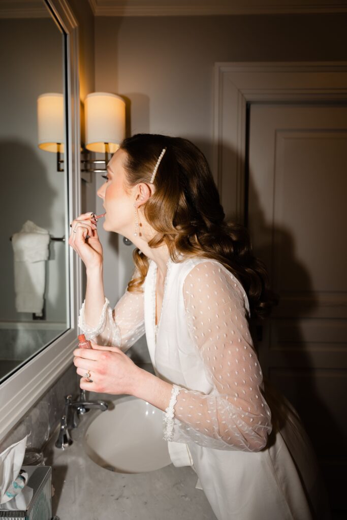 a glam flash portrait of the bride putting on lipgloss