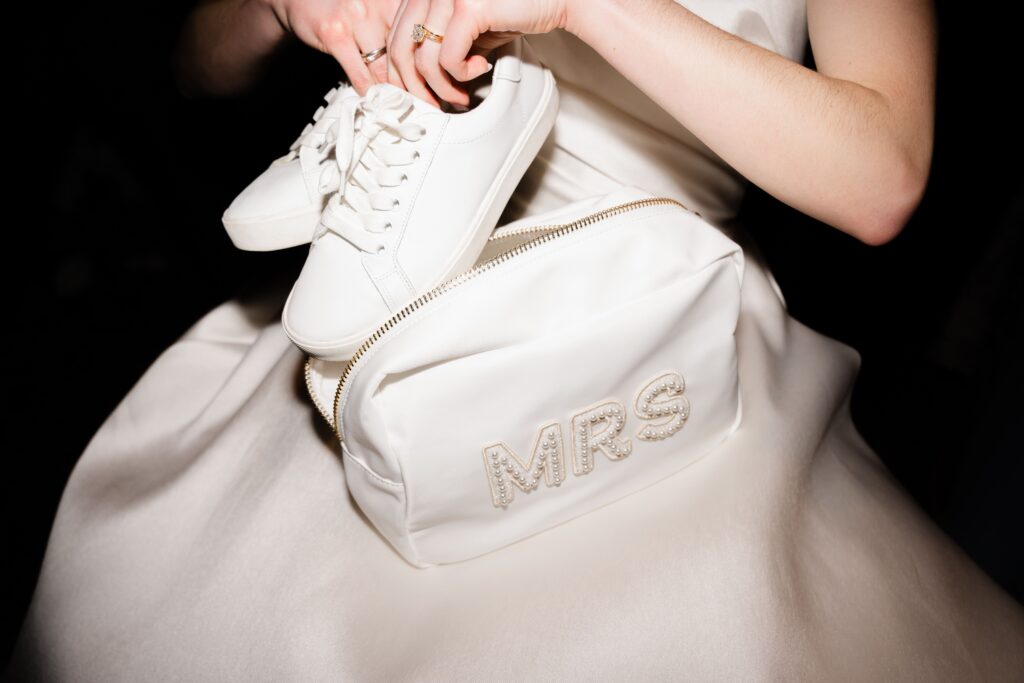 the bride pulls out her white sneakers during the wedding ceremony