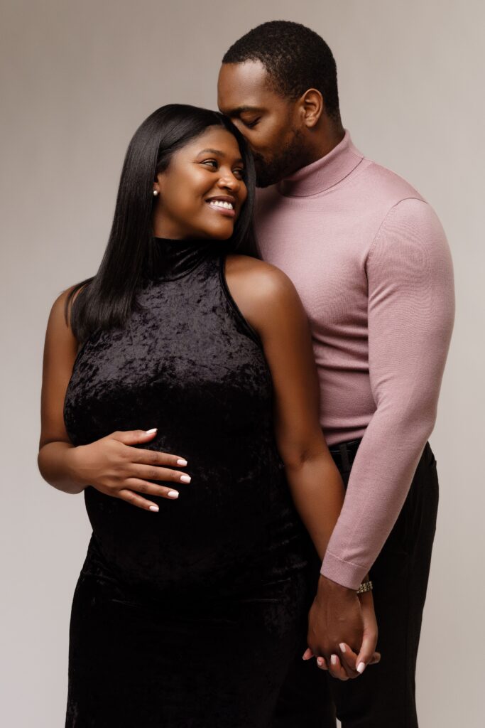 camille smiles at david behind her during their studio maternity photoshoot