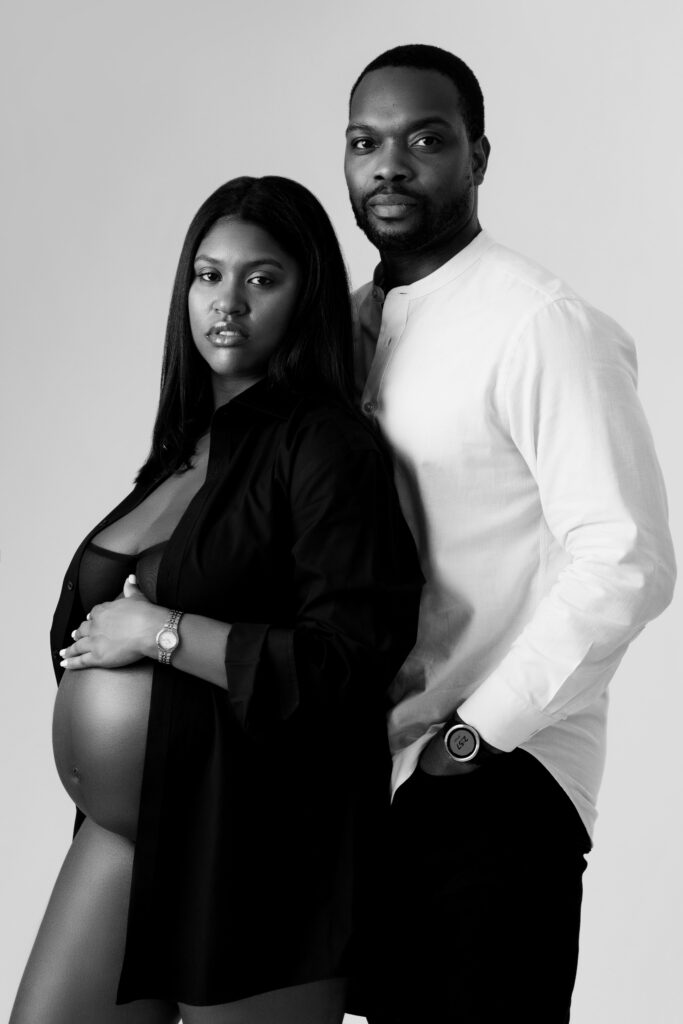 camille and david look at the camera during a studio maternity photoshoot