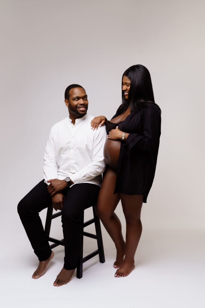 camille and david smile at each other at their studio maternity photoshoot