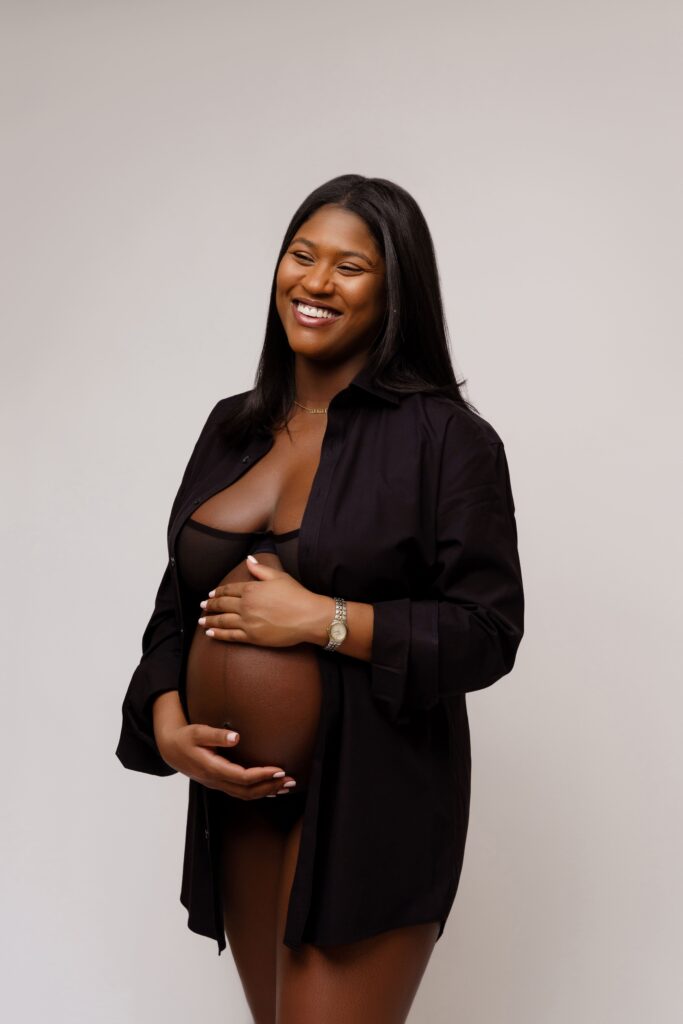 camille laughs as she gently holds her belly for her studio maternity photos