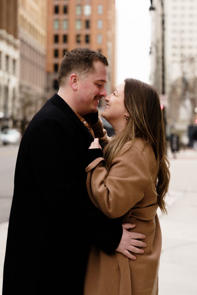 jane and john smile into a kiss during their detroit engagement photos