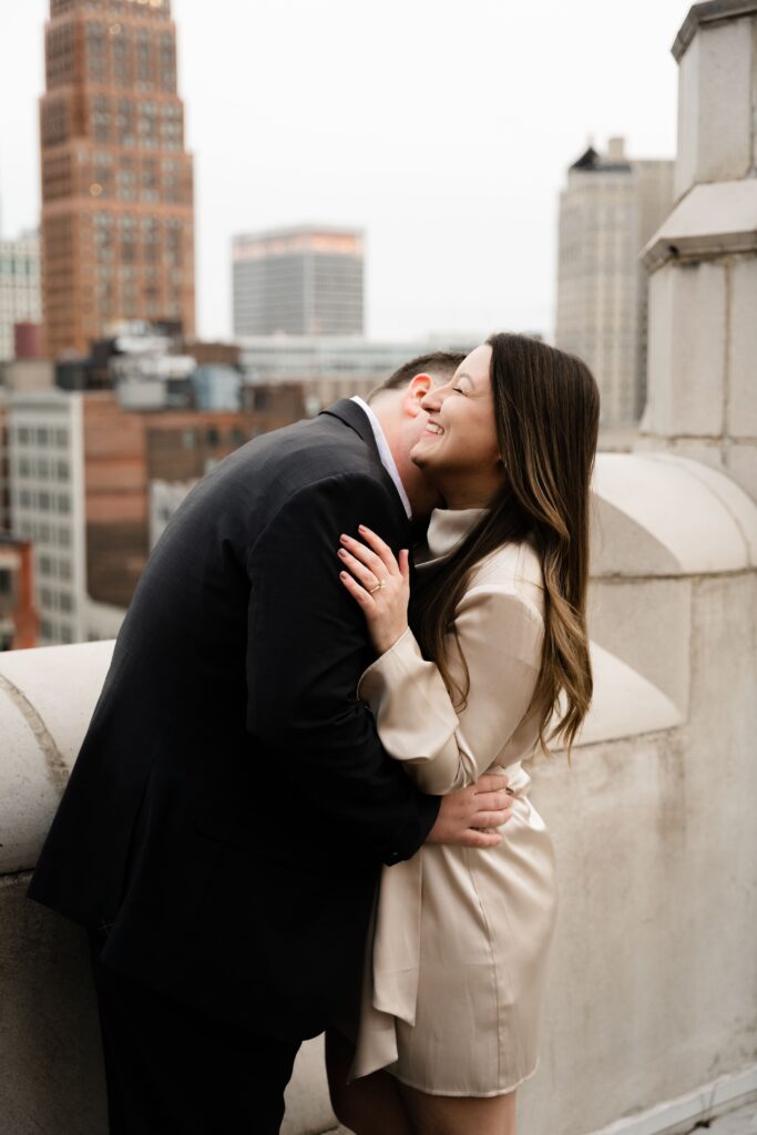 jane laughs as john presses a gentle kiss to her neck during their detroit engagement photos