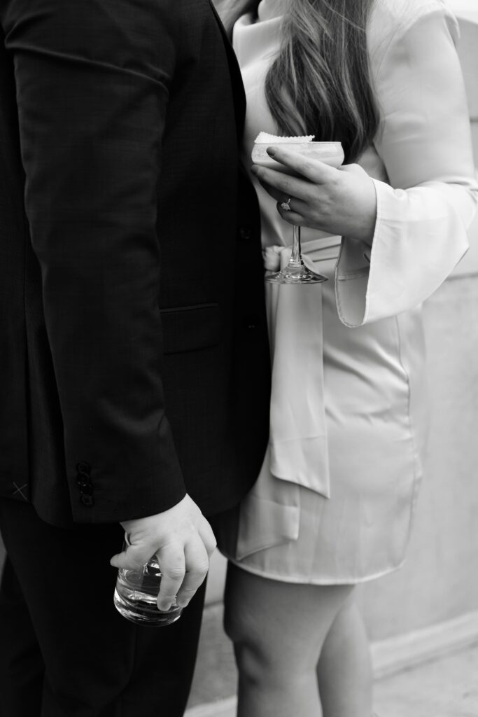 an engaged couple hold their drinks while standing close to each other