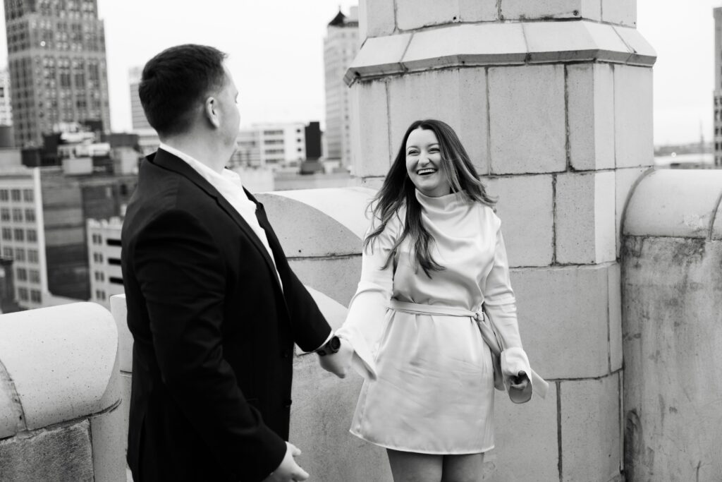 jane and john laugh together on a detroit rooftop