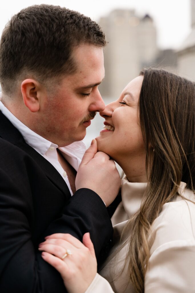 jane and john smile and lean in for a kiss during their detroit engagement photos