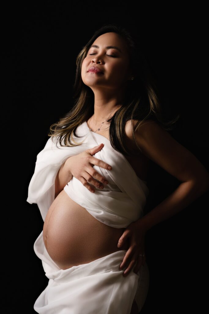 nat basks in the studio lighting with her baby belly out