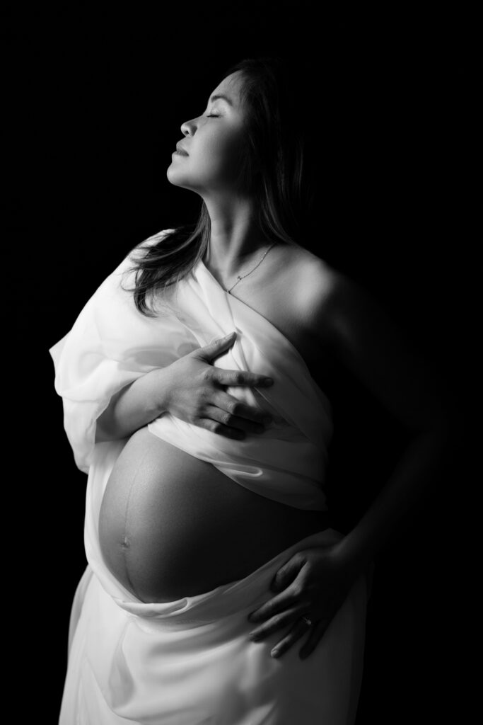 nat drapes white fabric around her body during her maternity session