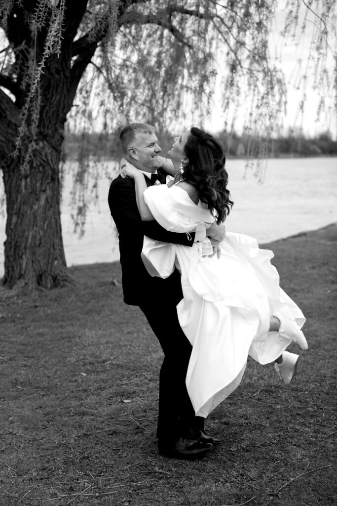the bride and groom laugh as he swings her around