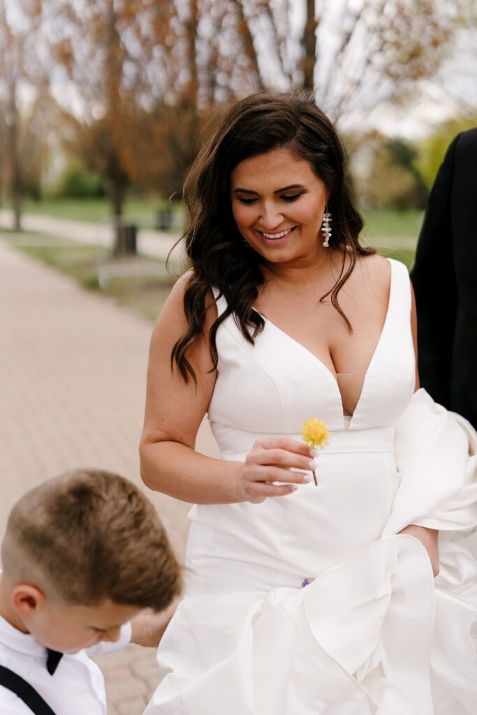 the bride smiles while holding a dandelion that her son gave her