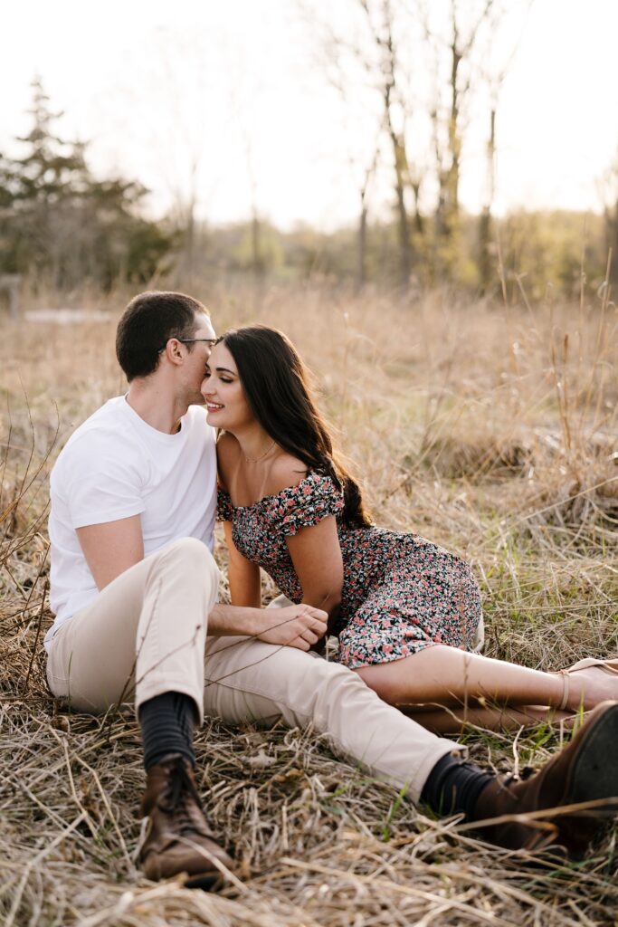 spencer and dalia lean in to each other while sitting on the ground and posing for their michigan engagement photographer