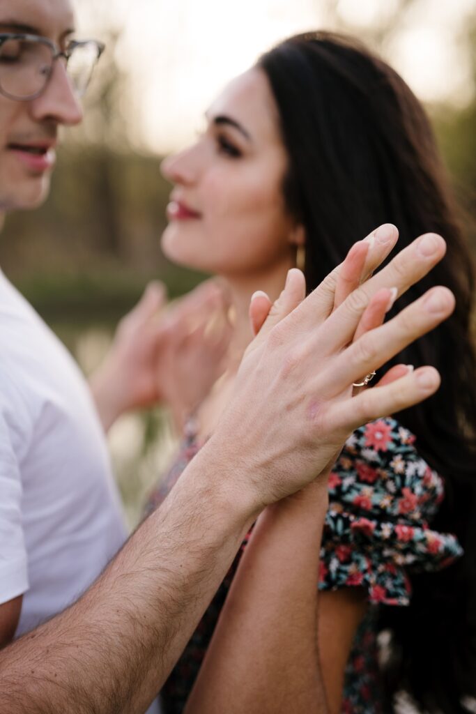 spencer and dalia flex their fingers while holding hands and posing for their michigan engagement photographer