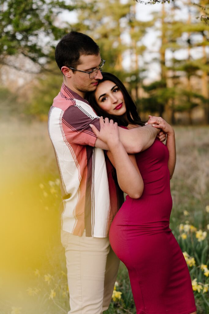 dalia looks at the ann arbor engagement photographer as spencer wraps his arm around her